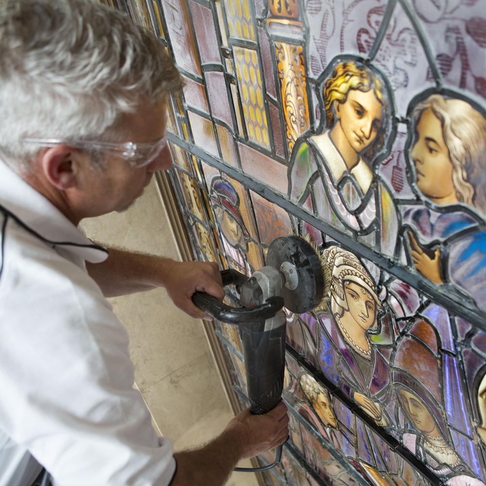 Workman cleaning stained glass window