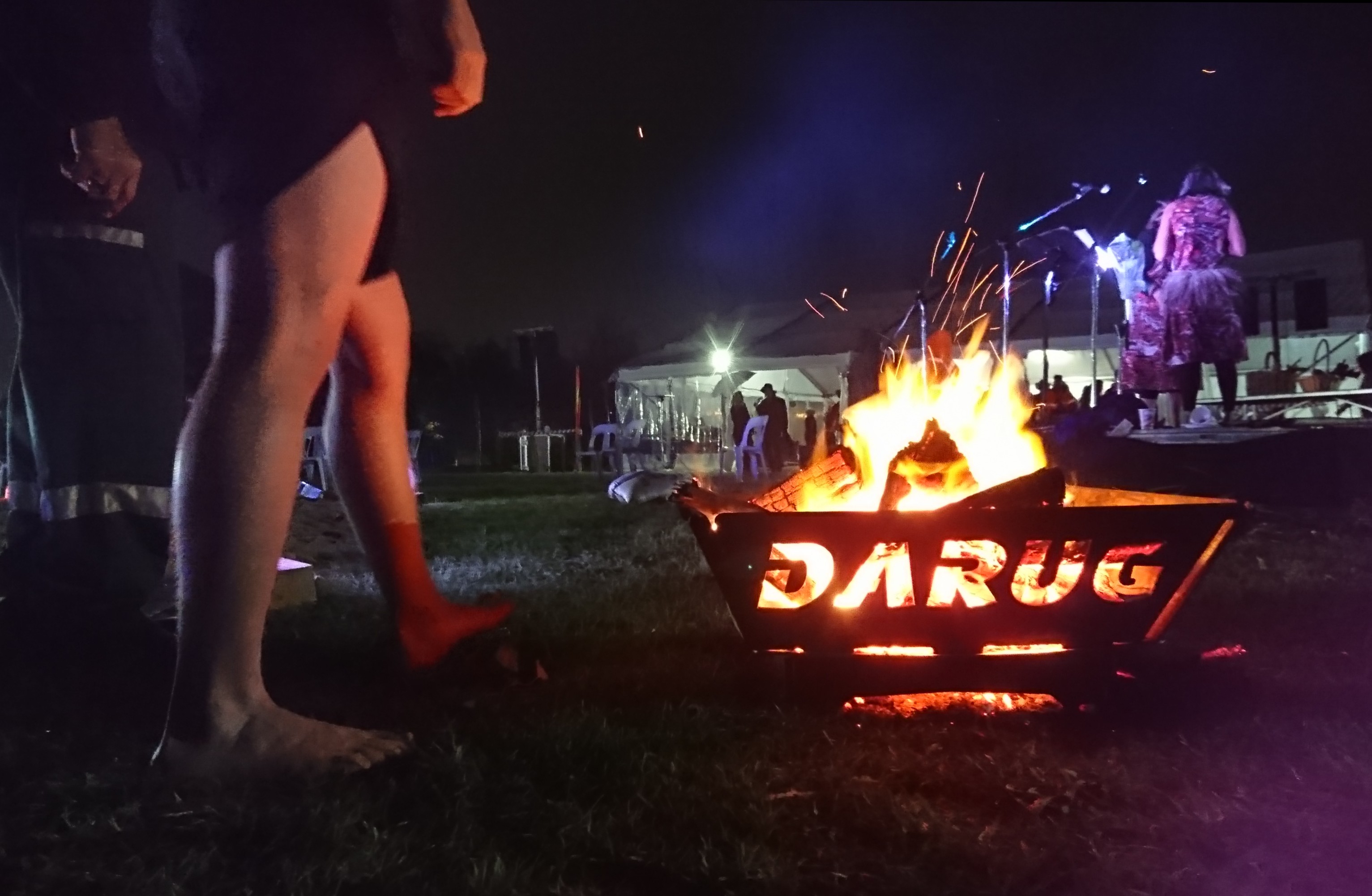 People are walking around a firepit that has the name "Darug" cut into it