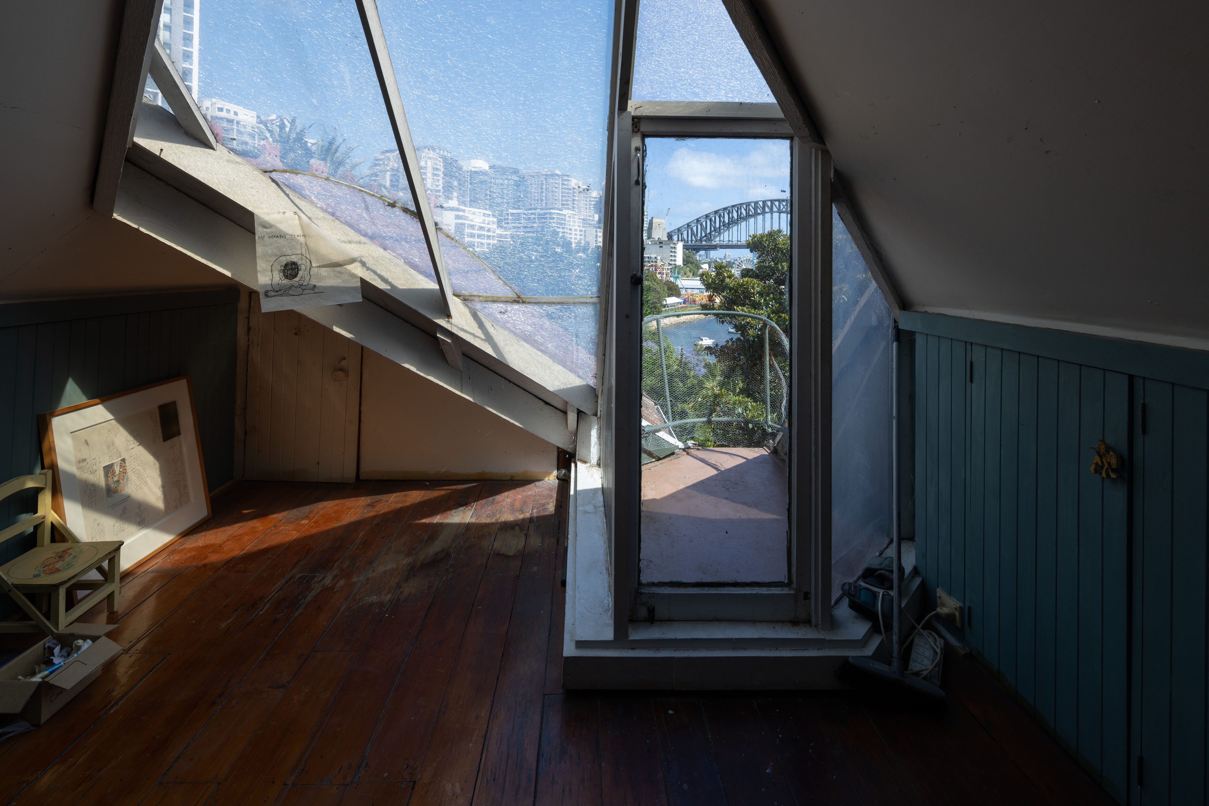 Mostly empty corner of a room with view outside a window of Sydney Harbour.