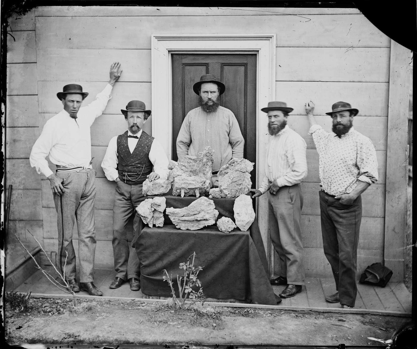 Group of miners standing in front of mine with gold nuggets