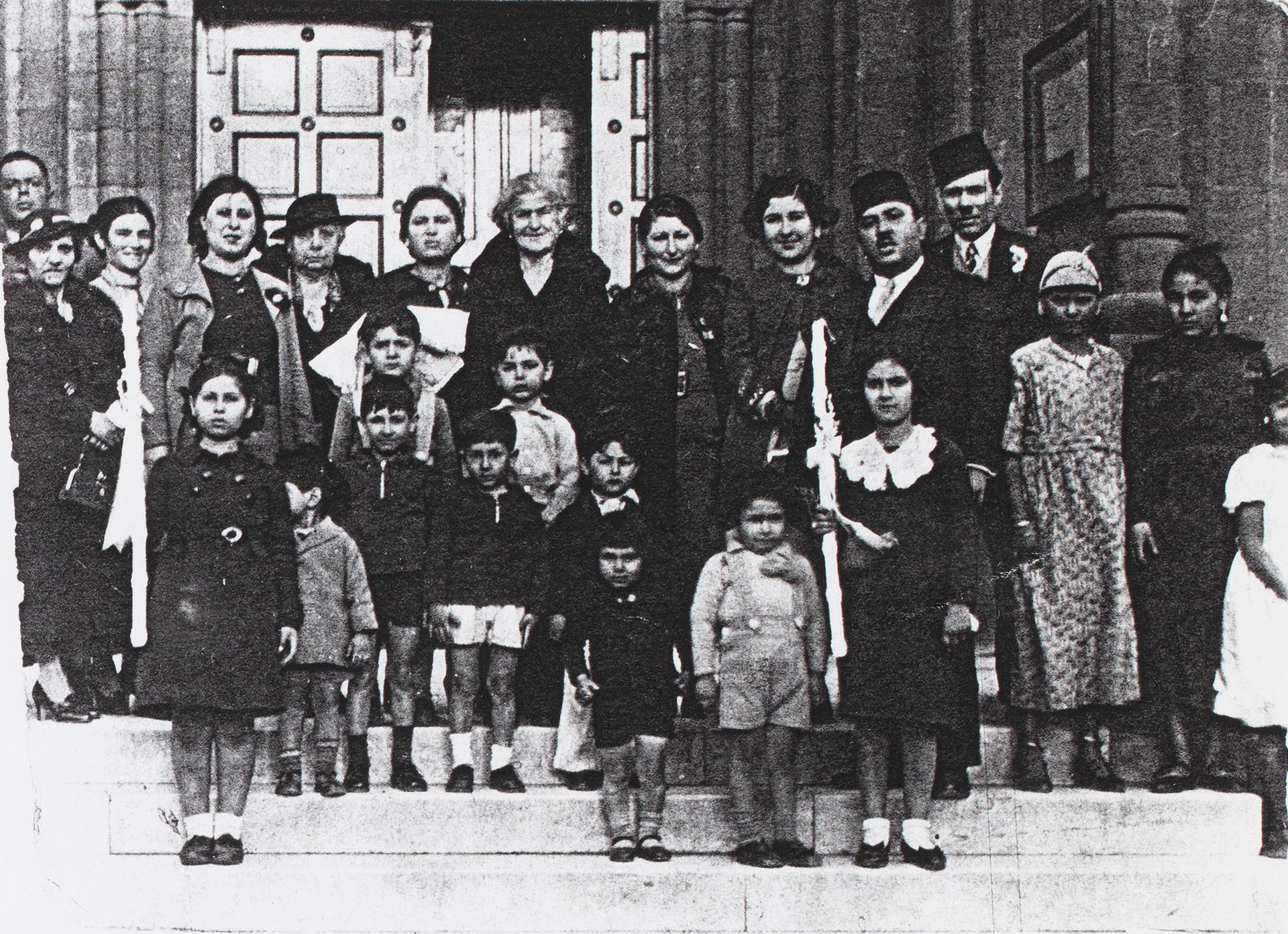 A group of people stand on the entrance steps to a building.