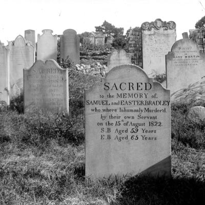 Black and white photograph of gravestones in a cemetery. 