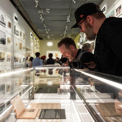 Two men looking at the display case in the Shot exhibition