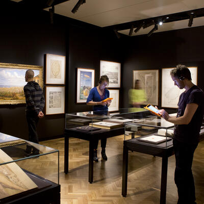 Men and women studying various exhibits under glass tables