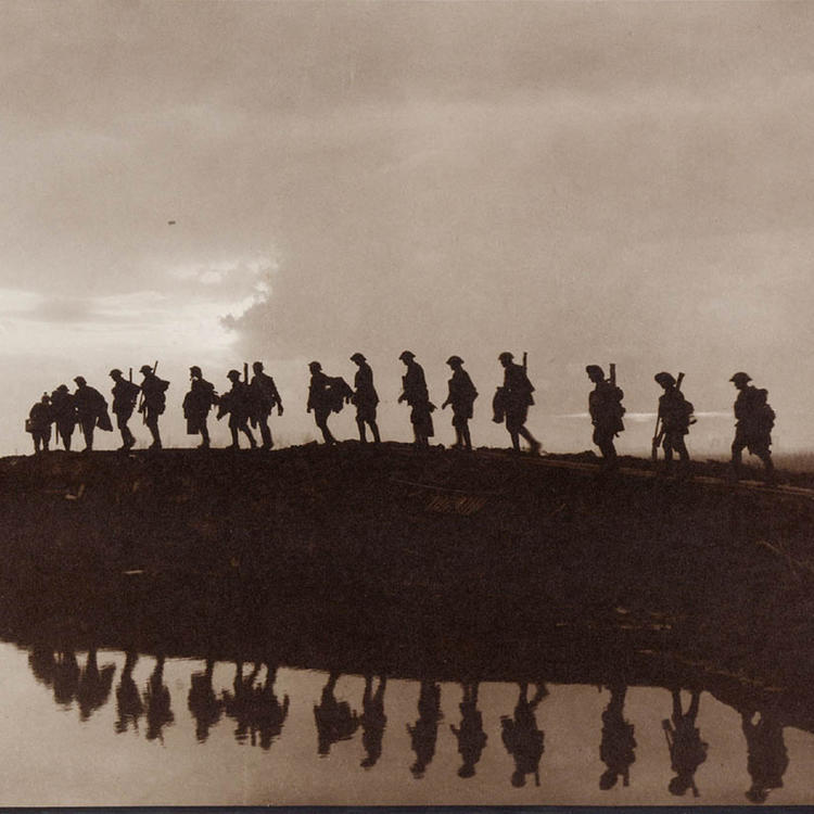 Men in silhouette walking along duckboards in the western front, 1917.