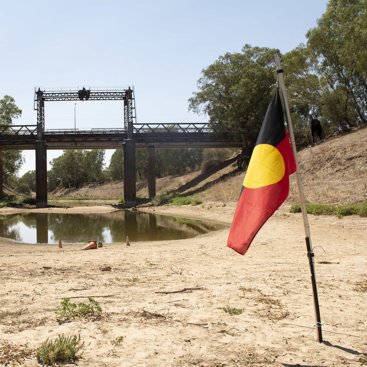 An Aboriginal flag is planted in a dry riverbed 