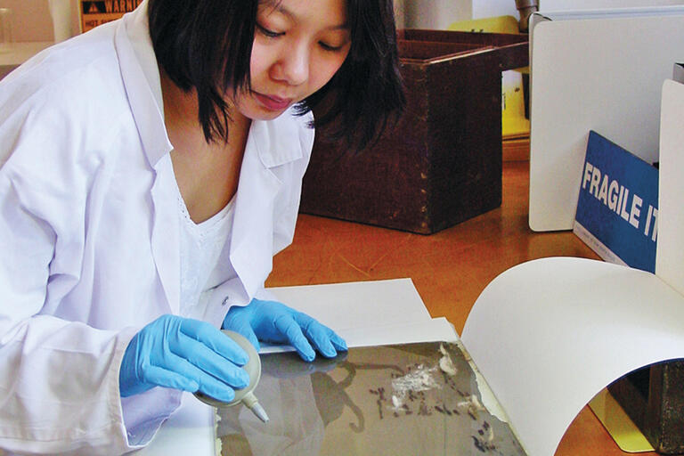 Woman carefully repairing glass portrait