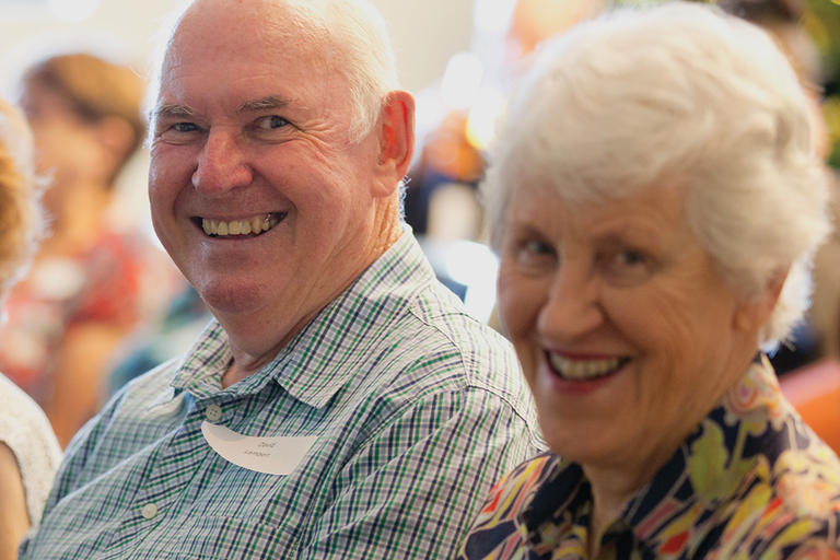 Two smiling older people in audience