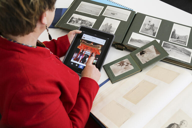 Woman using tablet to capture image from photo album