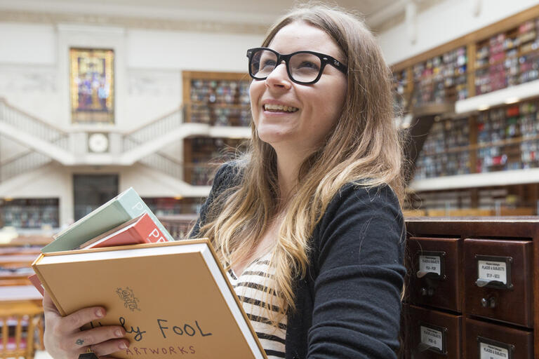 Women browsing shelves while holding books in the Mitchell Library Reading Room