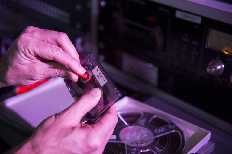 man's hands holding cassette tape