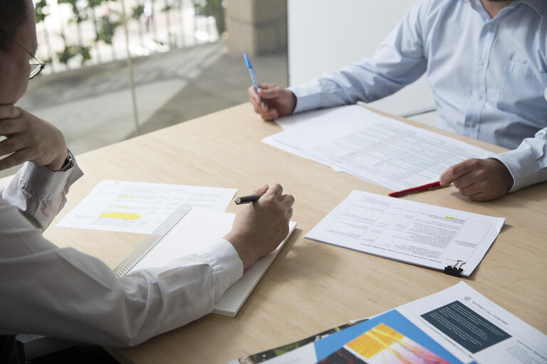 Two people writing on papers at desk