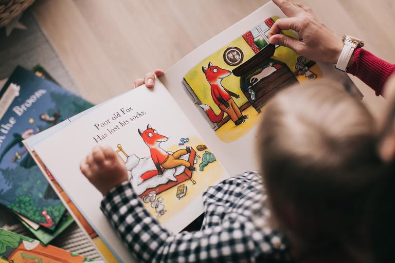 Child and adult looking at picture book