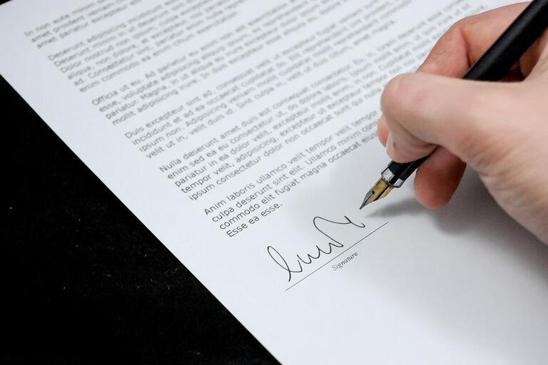 Hand with pen signing a document