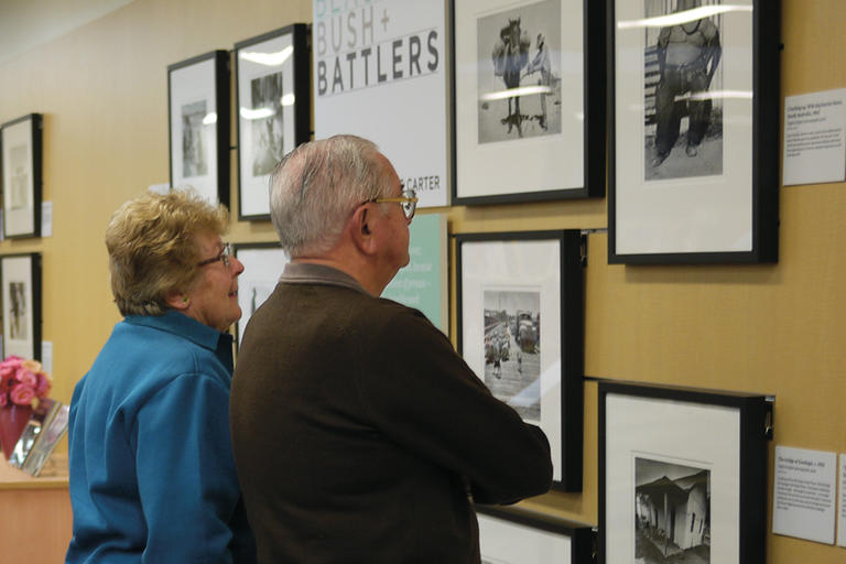 Man and woman looking at photos on wall