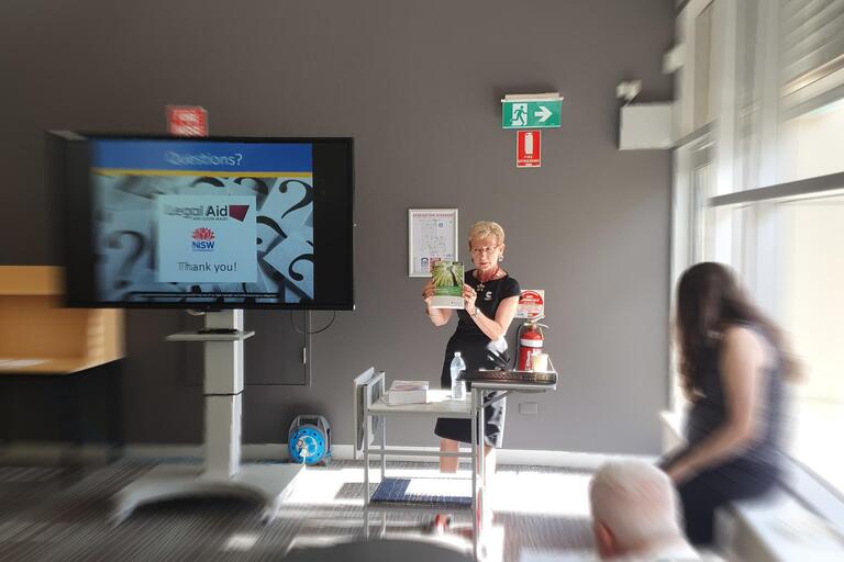 Woman giving presentation, holding up a book