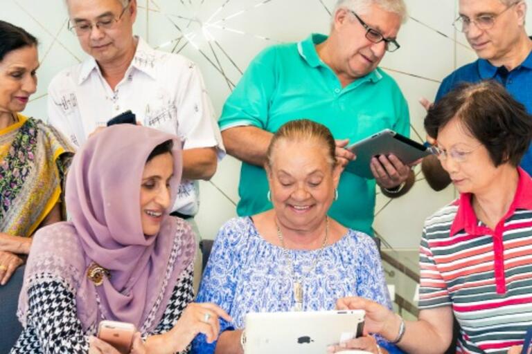 A group of older people from different cultural backgrounds learn how to use technology together