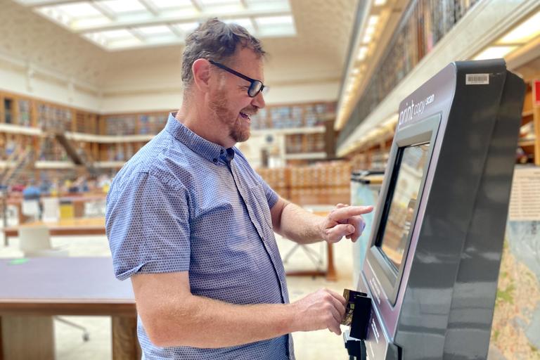 Man using Library copy card reload kiosks in Mitchell Reading Room 