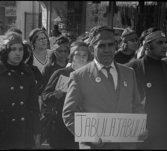 Man walking in protest group holding a placard