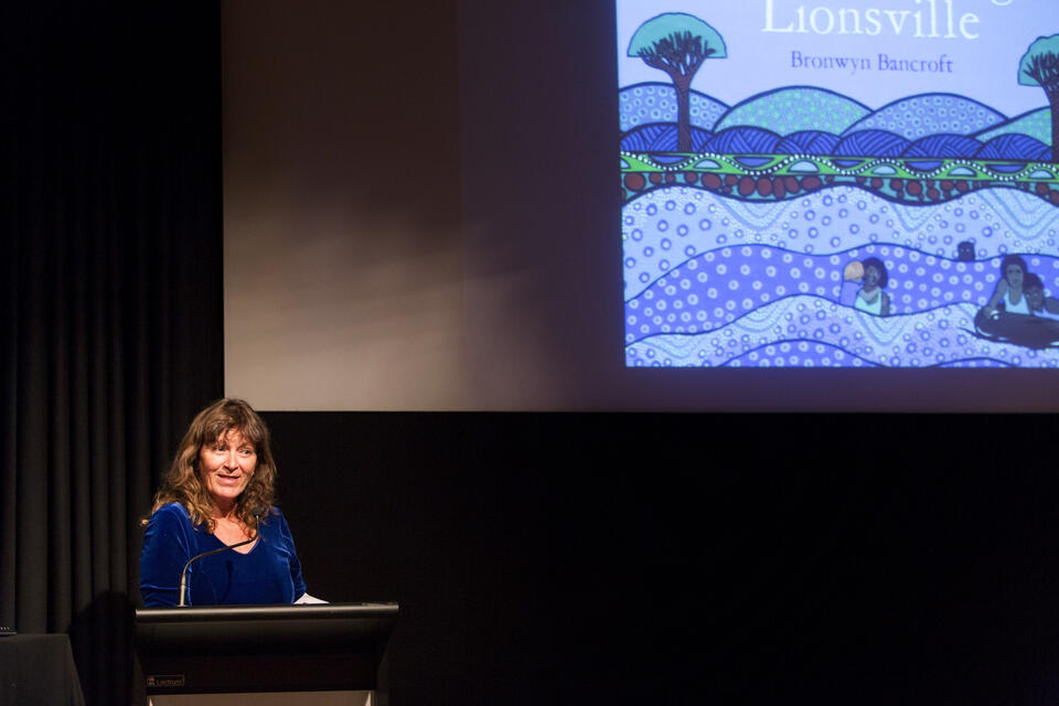 A woman speaking in front of a screen