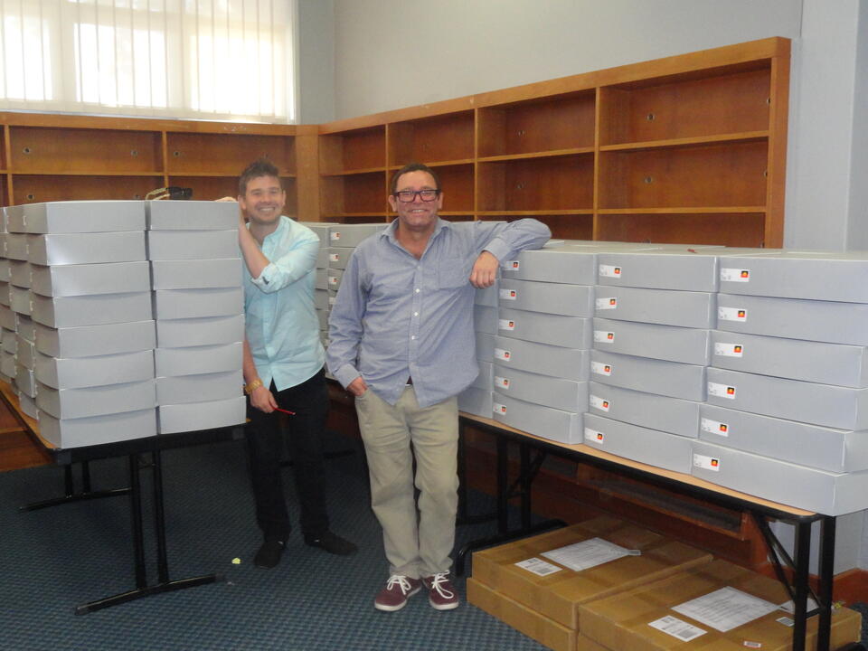 A man and a boy smiling, in front of a number of grey boxes