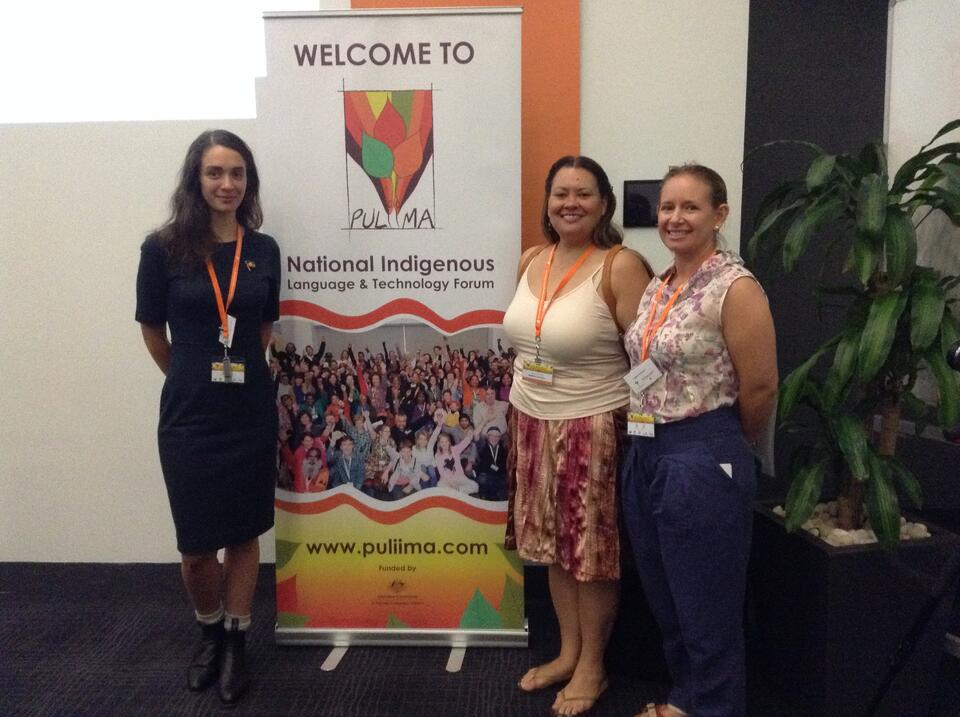 3 women standing close to a banner