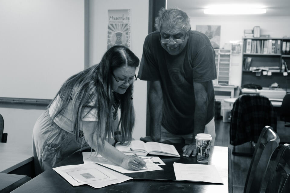 A man and a woman writing and looking on a notebook