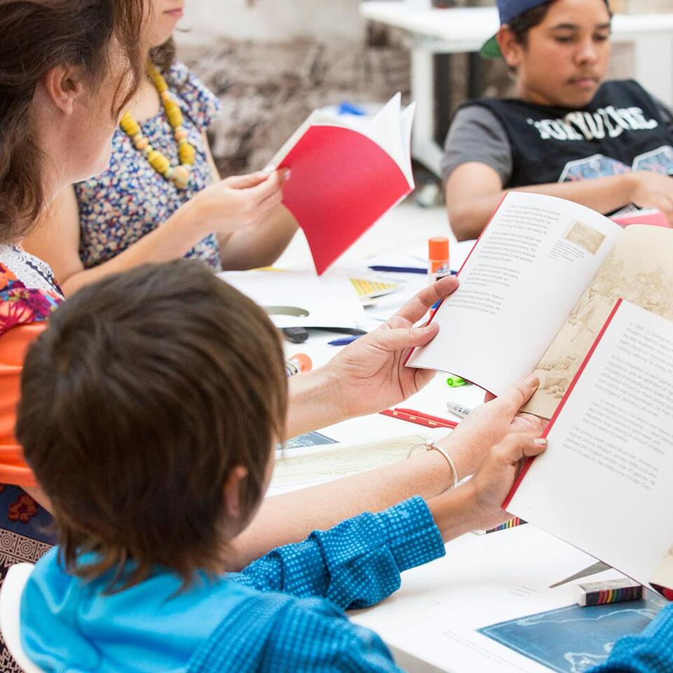 A child and a woman reading a book. A young guy is reading as well on the back